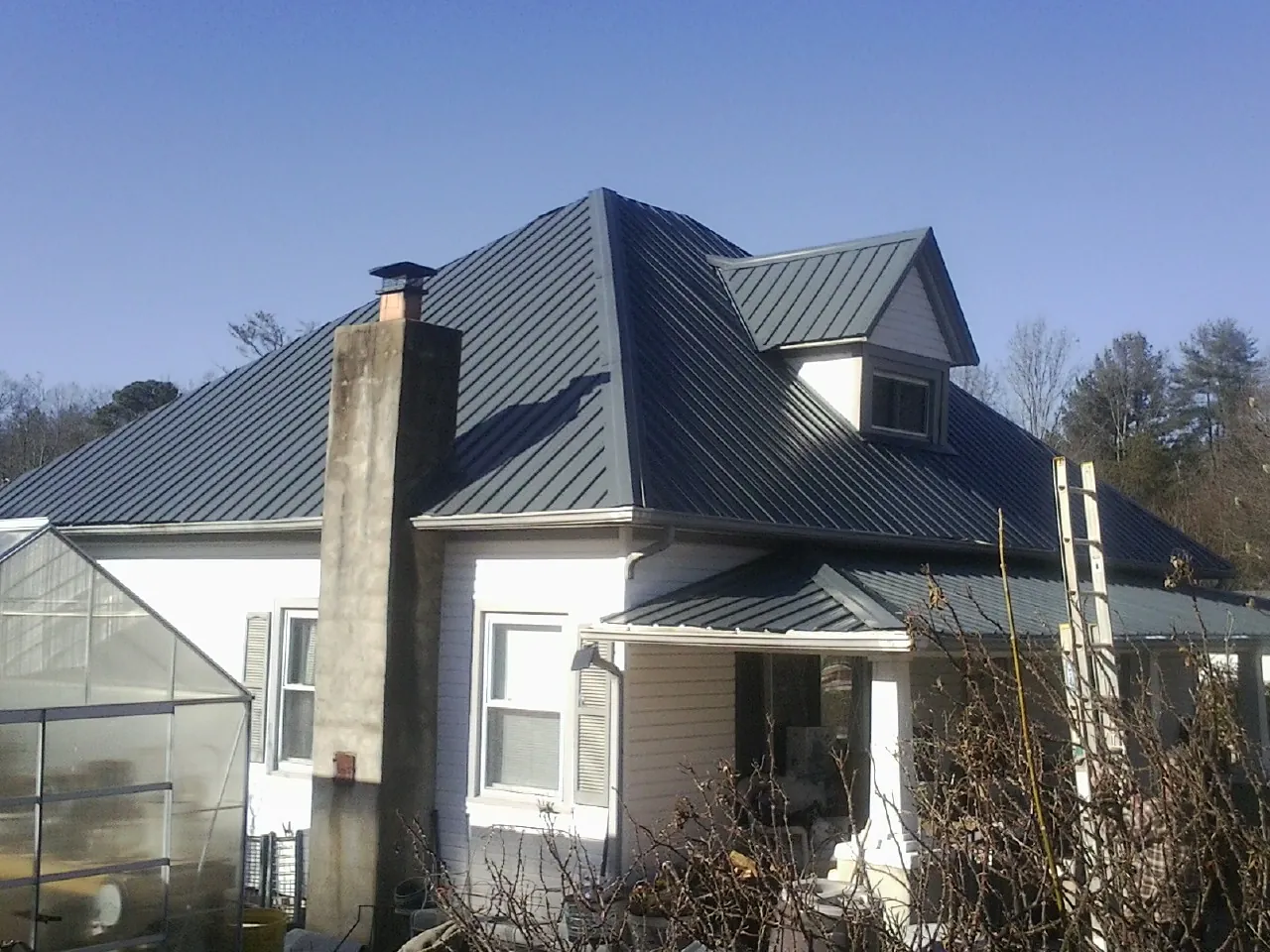 Dark blue standing seam metal roof on a white farmhouse with dormer — Slate & Tile Roof Repair by Roofing Brothers in Armada