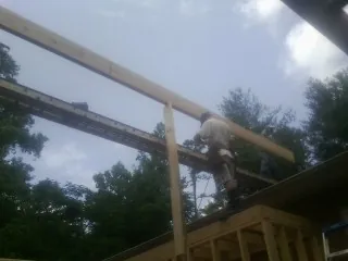 Carpenter setting a ridge beam over a new addition frame — Ice Dam Removal by Roofing Brothers in Armada