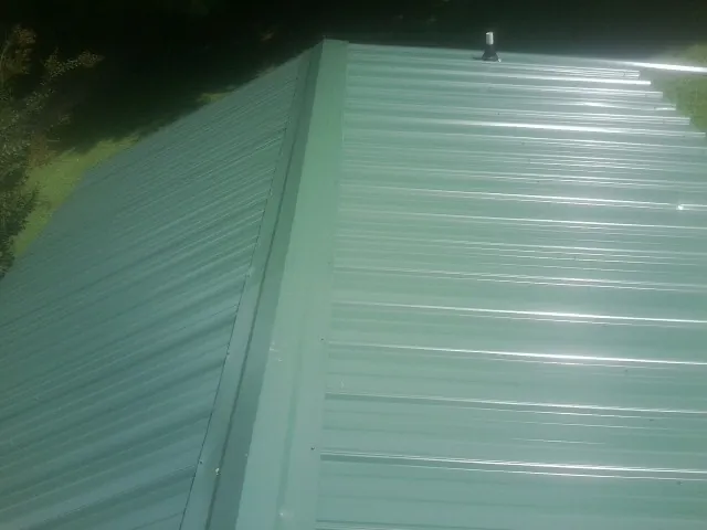New green metal panels meeting at the ridge of a roof — Flat Roof Repair work by our crew in Armada