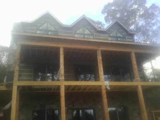 Dormers and porch framing on a large log home under construction — Roof Coating work by our crew in Armada
