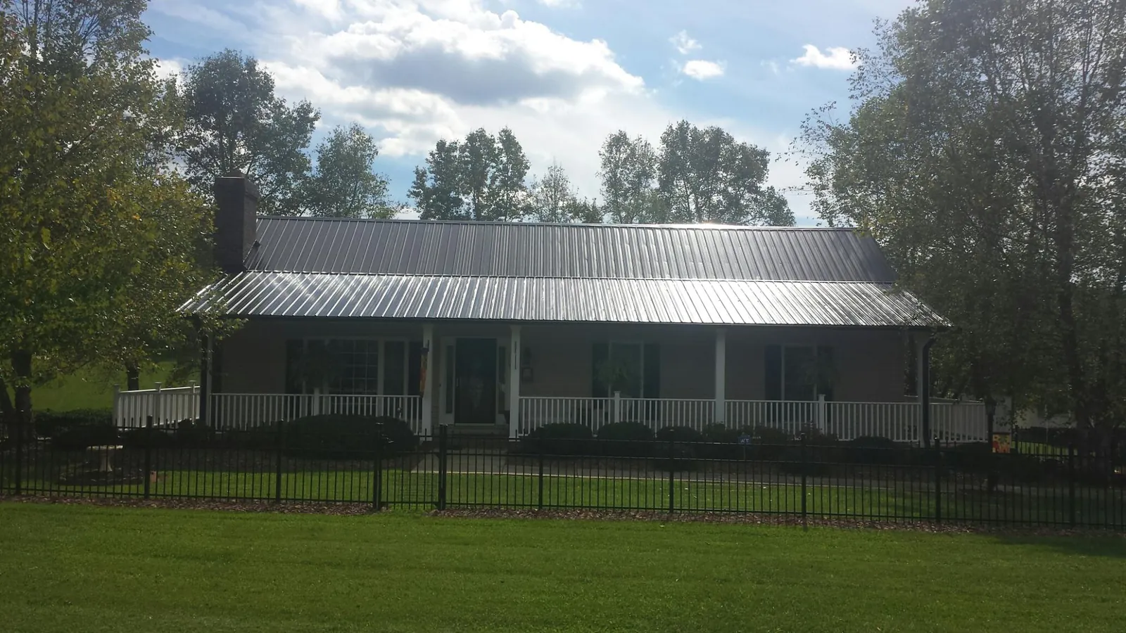 Gray metal roof on a brick ranch with a full width front porch — Gutter Guard Installation work by our crew in Armada