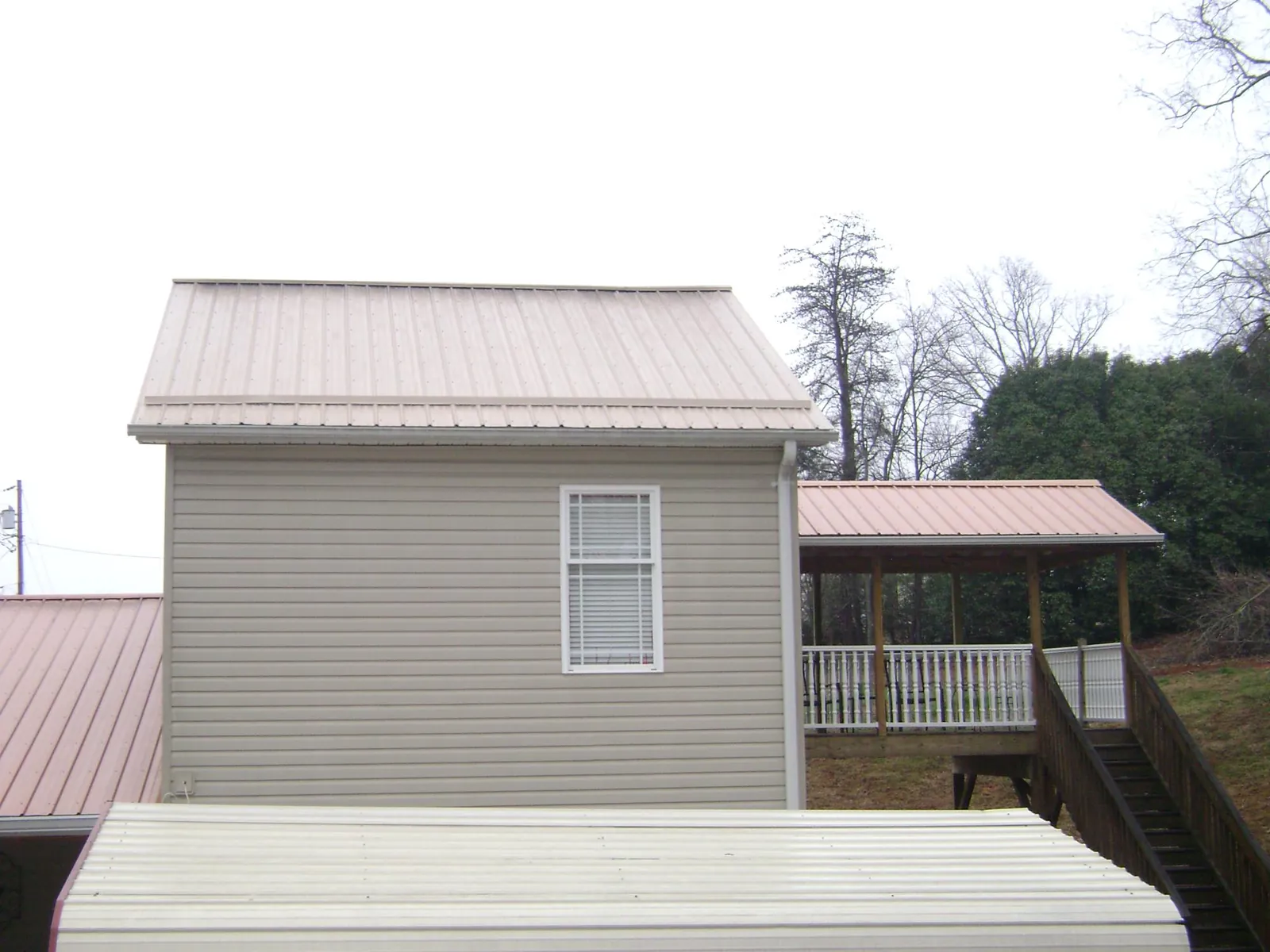 Tan metal roofs on a two story addition and attached porch, from a Roof Replacement job in Armada