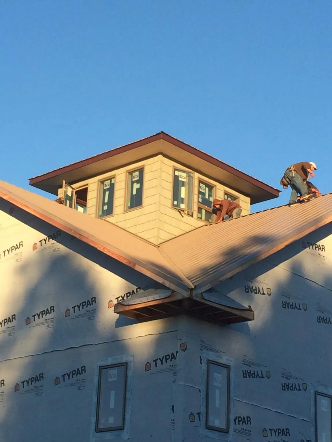 Roofers working around a rooftop cupola on a new metal roof at sunset — Roof Waterproofing in Armada by Roofing Brothers